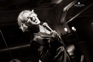 blonde Frau singedn vor schwarzem Hintergrund