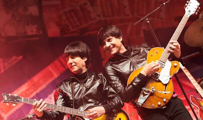Zwei Beatles mit Gitarren auf vorderer Seite von Bühne, führt zum Kalendereintrag