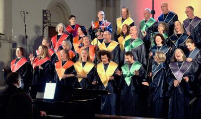 Gruppe aus singenden Frauen und Männern in bunten Roben