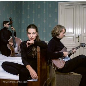 Trio Kronthaler sitzend in Zimmer mit Instrumenten
