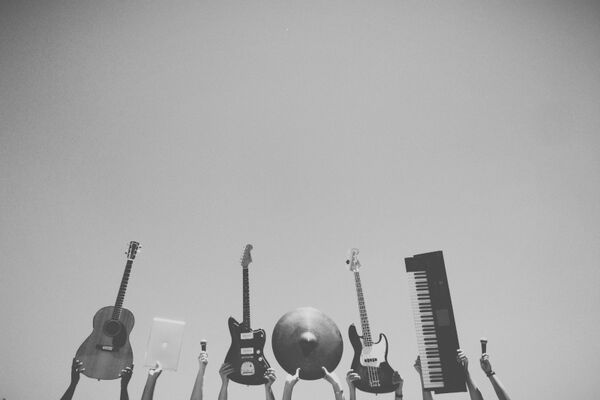 Hände die Musikinstrumente in die Luft halten Link führt zu den Fächerangeboten der Musikschule